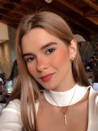 Woman in a white sweater with a small cross necklace